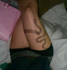 a woman laying on top of a bed with a tattoo on her leg and legs