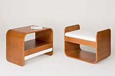 two wooden tables sitting next to each other on a white surface with a book on top