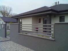 a house that is next to a fence and some gravel on the ground in front of it