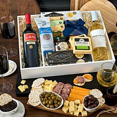 an assortment of wine, cheese and crackers in a gift box on a table