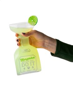 a hand holding a margarita bottle with a lime in it and a glass filled with liquid