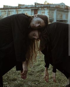 two people bending over in the grass with their hands on each other's head