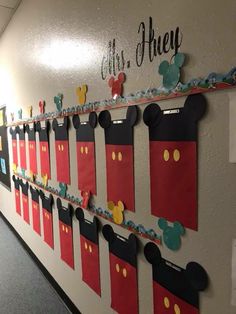 a bulletin board with mickey mouse magnets on it's side in an office hallway