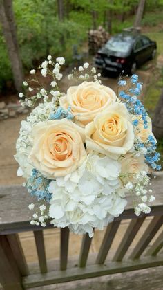 a bouquet of flowers sitting on top of a wooden bench in front of a car