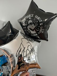 someone is holding some black and silver balloons