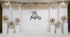 a white room with flowers and the words the bachelor on it's wall behind some pedestals