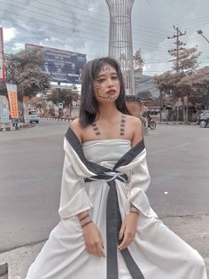 a woman in a white dress standing on the street