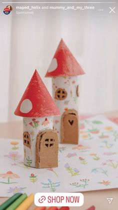 two little houses made out of cardboard sitting on top of a table next to colored crayons