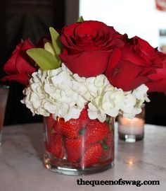 red roses and white hydrangeas in a glass vase on a marble counter top