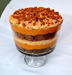 a layered dessert in a glass dish on top of a white tablecloth covered table