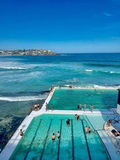 people are swimming in an outdoor pool next to the ocean