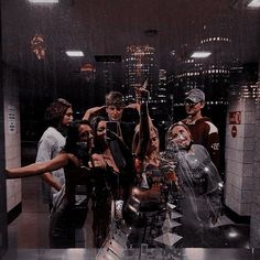 a group of people standing around each other in a room with mirrors on the wall