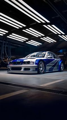 a blue and white car is parked in a parking garage with lights on the ceiling