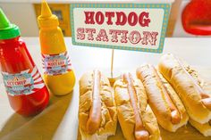 hotdogs and condiments on a table with a sign that says hot dog station