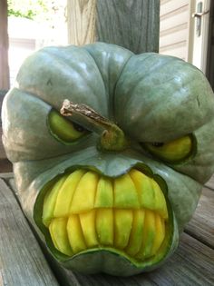 a green pumpkin with an angry face made out of it's mouth and tongue