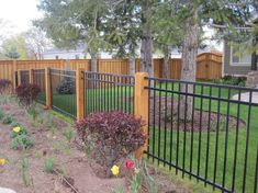 a fenced in yard with flowers and trees