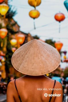 the back of a woman wearing a straw hat with lanterns in the sky behind her