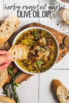 a bowl of olive oil dip with bread on the side and herbs sprinkled around it