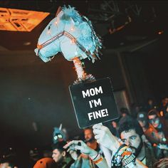 a person holding up a sign that says mom i'm fine in front of a crowd