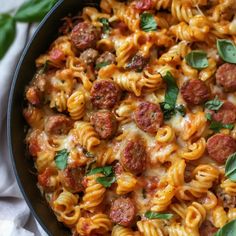 a skillet filled with pasta and meatballs covered in sauce, cheese and herbs