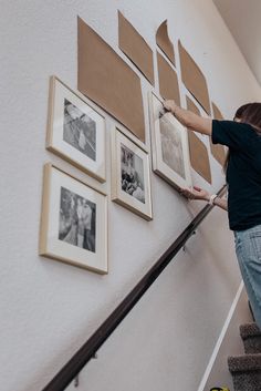 a woman is climbing up the stairs with her hand on the railing and pictures hanging on the wall