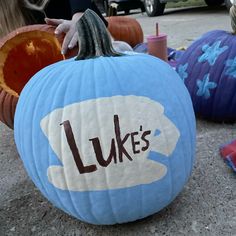 three pumpkins with the words luke's painted on them sitting in front of other pumpkins