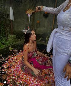 a woman is sitting on the ground covered in flowers