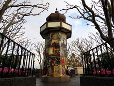 there is a tall tower with pictures on it in the middle of some bushes and trees