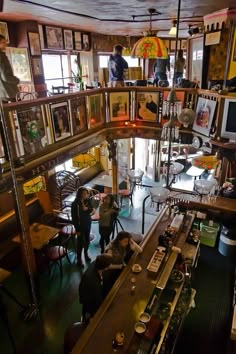 people are standing in a room with many pictures on the wall and shelves above them