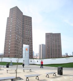 people are walking around an empty park with benches