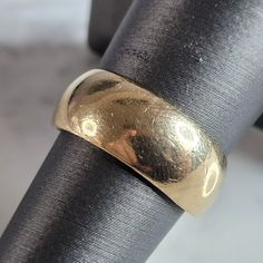 a close up of a gold ring on top of a black piece of metal with a white background