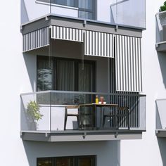 an outdoor table and chairs in front of a building with blue stripes on the side