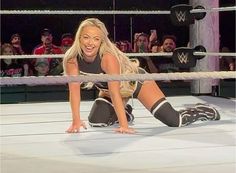 a woman kneeling on the ground in front of a wrestling ring