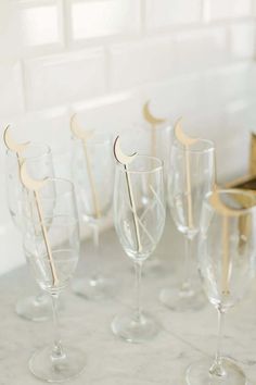 several wine glasses with wooden sticks sticking out of them on a marble countertop in front of a window