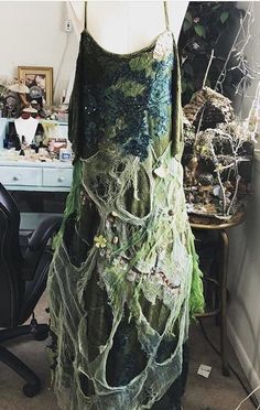 This one of a kind made to order dress is a beautiful amalgamation of everything beautiful and magical about the woods and beautiful earth greens with tones of browns and cobwebs silver because covers the front with various elements that dangle throughout as I've collected over the years by fairies this dress is 100% magical and very comfortable extremely lightweight with a pull over design it fits anywhere from an extra extra small on way up to a 2X large it is a one-of-a-kind item and will tru Green Fantasy Dress For Costume Party, Fairy Style Green Dress For Costume Party, Green Fairy Dress For Costume Party, Whimsical Green Dress For Costume Party, Fairycore Green Dress For Costume Party, Dress With Wings, Fairy Clothes, White Witch, Green Earth