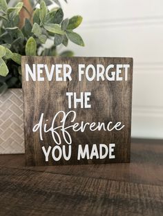 a wooden sign that says never forget the difference you made on it next to a potted plant