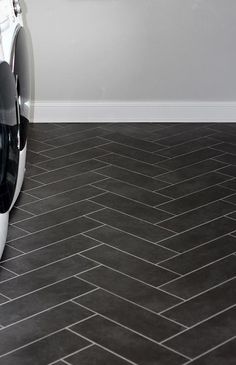 a white car parked on top of a black tile floor next to a gray wall