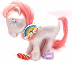 a white pony with pink hair and rainbow manes standing next to candy canes