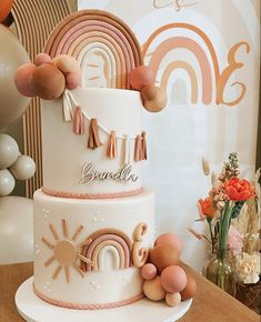 a three tiered cake decorated with balloons and tassels is on a table