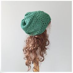 a woman with curly hair wearing a green crochet beanie hat on top of her head