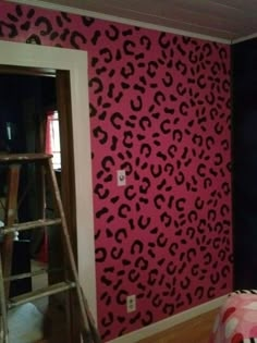 a pink and black leopard print wallpaper in a room with a ladder leaning against the wall