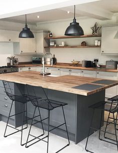 a kitchen with an island and bar stools next to the counter top in front of it