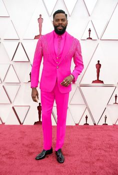 a man in a pink suit and black shoes on the red carpet at an oscars