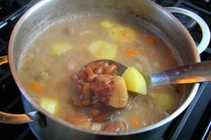 a pot filled with soup and beans on top of a stove