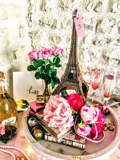 a table topped with pink flowers next to a bottle of wine