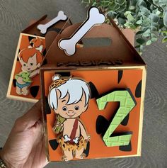 someone holding up two boxes with numbers and cartoon characters