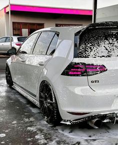 the back end of a white car covered in snow