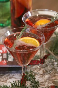 two glasses filled with red wine and garnished with rosemary, sitting on a table