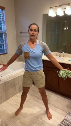 a woman standing in front of a bathtub with her hands out to the side