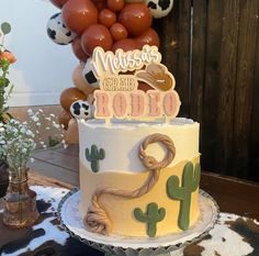 a birthday cake with a cowboy theme on the top is sitting on a table in front of balloons